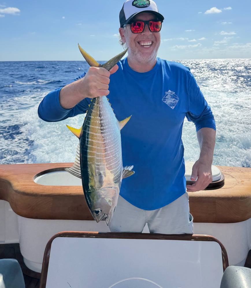 Guest smiling with a yellowfin tuna offshore